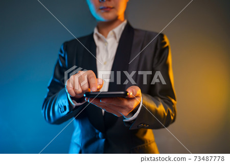 Business woman holding smart phone in black suit. Business woman holding smart phone in black suit. 73487778