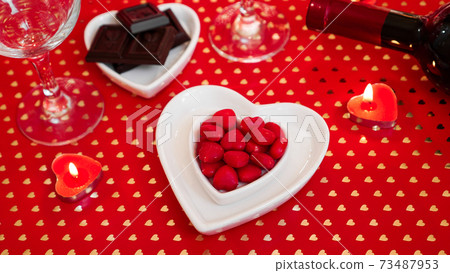 Valentines day. Bottle of vine, glasses, red roses, candles - red background Valentines day. Bottle of vine, glasses, red roses, candles - red background 73487953