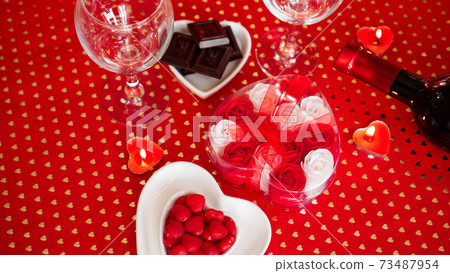 Valentines day. Bottle of vine, glasses, red roses, candles - red background 73487954