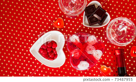 Valentines day. Bottle of vine, glasses, red roses, candles - red background Valentines day. Bottle of vine, glasses, red roses, candles - red background 73487955