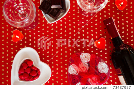 Valentines day. Bottle of vine, glasses, red roses, candles - red background Valentines day. Bottle of vine, glasses, red roses, candles - red background 73487957