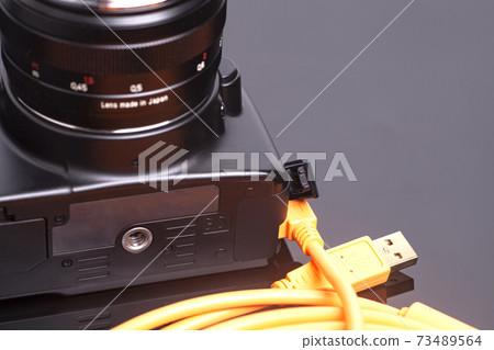 Digital photo camera with orange rolled cable Digital photo camera with orange rolled cable 73489564