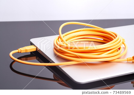 laptop with orange rolled cable laptop with orange rolled cable 73489569