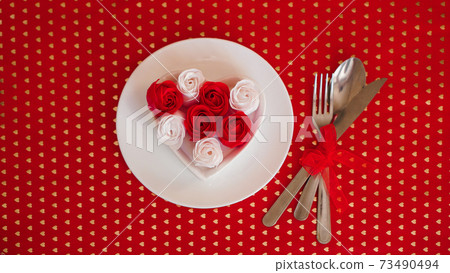 A white plate with a knife and fork on a bright red background A white plate with a knife and fork on a bright red background 73490494