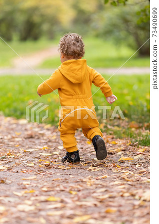 Little boy in yellow overalls walking first steps in autumn park Little boy in yellow overalls walking first steps in autumn park 73490699