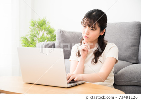 A woman with a difficult expression while looking at the computer screen A woman with a difficult expression while looking at the computer screen 73491126