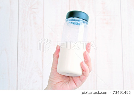 Female hand with a protein-filled tumbler 73491495