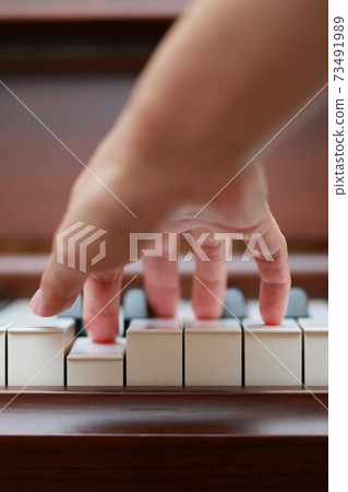 Female finger playing walnut upright piano Female finger playing walnut upright piano 73491989
