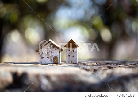 Two small houses with sunbeams back 73494198