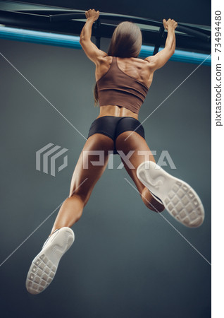 woman pumping up muscles pull-ups exercises in gym woman pumping up muscles pull-ups exercises in gym 73494480