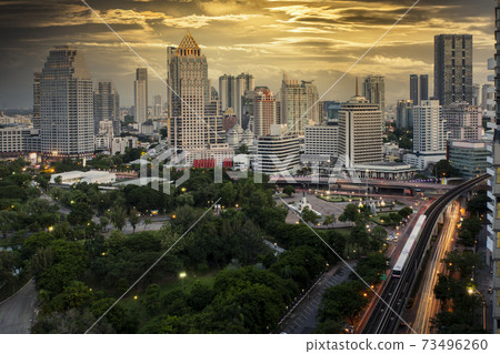 Bangkok business district with the public park area anf the sky train in the foreground at sunset time. 73496260