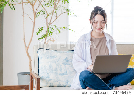 Young woman sitting on the couch and teleworking 73496459