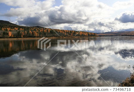 Autumn landscape on the taiga Siberian river with the reflection of the sky on the surface of clear water. Autumn landscape on the taiga Siberian river with the reflection of the sky on the surface of clear water. 73496718