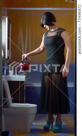 a man disguised as a woman pouring boiling water from a kettle into the toilet. a man disguised as a woman pouring boiling water from a kettle into the toilet. 73496972