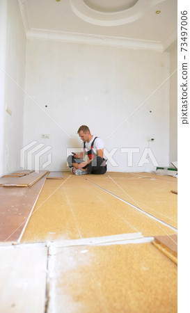 Builder in renovated room lying on floor using smartphone Builder in renovated room lying on floor using smartphone 73497006