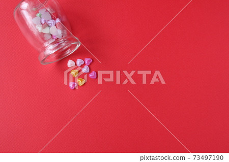 Rhine pink yellow hearted cards poured out of a glass can of flasks on a red background with a copyspace valentine's day Rhine pink yellow hearted cards poured out of a glass can of flasks on a red background with a copyspace valentine's day 73497190