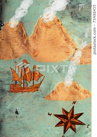 Nautical chart with illustrations of a sailing vessel, a compass rose and volcanic islands in order of antiquities on a natural wooden birch bark background 73498455