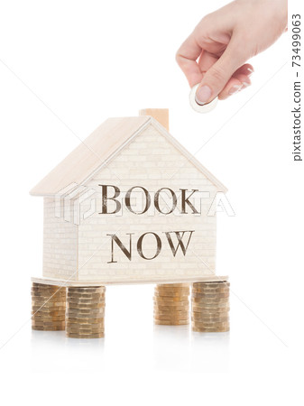 Wooden house model standing on coins and hand 73499063