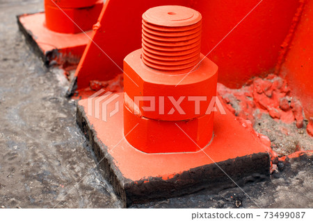 The red metal support is bolted to the concrete base with large bolts. Fixing a tower or tower to The red metal support is bolted to the concrete base with large bolts. Fixing a tower or tower to 73499087