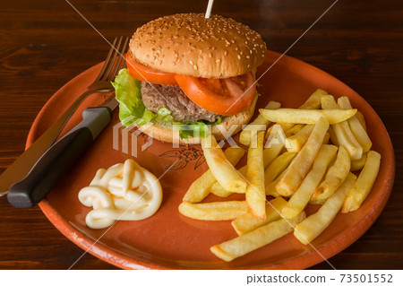 Hamburger salad and tomatoes with fried potatoes on an earthenware plate 73501552