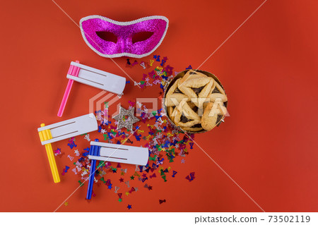 Jewish carnival Purim celebration on hamantaschen cookies, noisemaker and mask 73502119