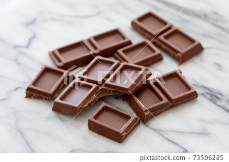 Broken chocolate bar on a marble table 73506285
