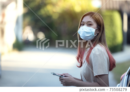 Asia woman wearing a medical mask and using a phone outdoors 73508279