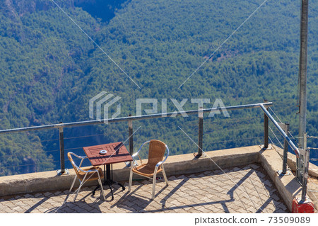 Table and chairs on a viewing platform for rest on a top of Tahtali mountain near Kemer, Antalya province in Turkey 73509089