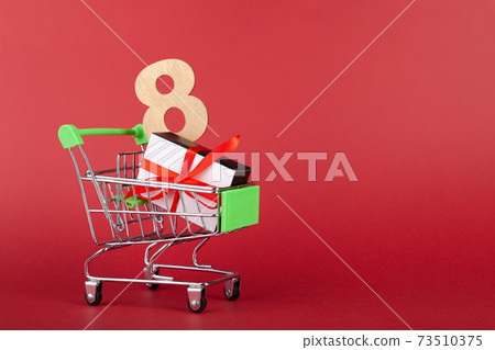 Red heart, gift box with red ribbon inside mini grocery cart on colored background Red heart, gift box with red ribbon inside mini grocery cart on colored background 73510375