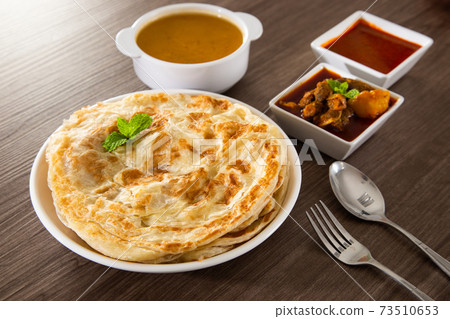 Roti Parata or Roti canai with lamb curry sauce. 73510653