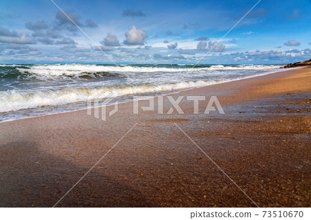 Sandy beach, small waves and blue sky with clouds Sandy beach, small waves and blue sky with clouds 73510670