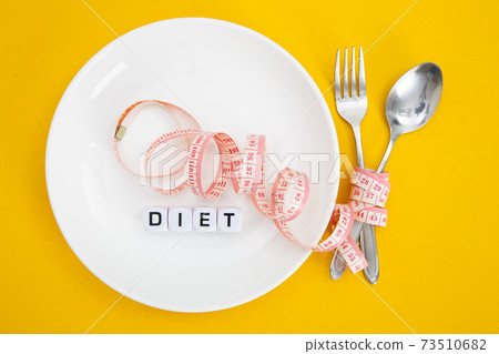 Measuring tape on a fork and knife - diet concept 73510682