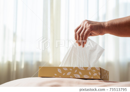 Senior women hand picking napkin/tissue paper from the tissue box 73513795