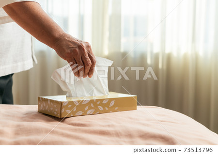 Senior women hand picking napkin/tissue paper from the tissue box 73513796