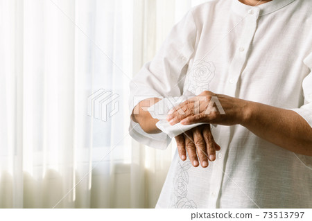 Senior woman cleaning her hands with white soft tissue paper. isolated on a white backgrounds 73513797