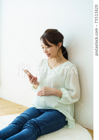 看著智能手機的婦女的產假 73513820