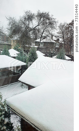The roofs of houses and trees are covered with white snow. Winter. The roofs of houses and trees are covered with white snow. Winter. 73514440