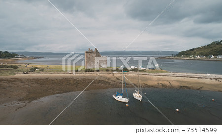 Seascape at castle ruins aerial. Ocean bay with sailboats, yachts, ships. Historic Scottish heritage Seascape at castle ruins aerial. Ocean bay with sailboats, yachts, ships. Historic Scottish heritage 73514599