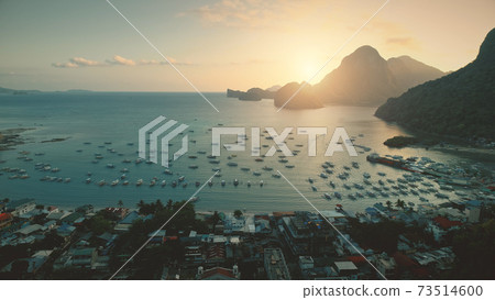 Aerial sunset at ocean harbor with boats of tropic port town cityscape. Buildings, lodges, homes Aerial sunset at ocean harbor with boats of tropic port town cityscape. Buildings, lodges, homes 73514600