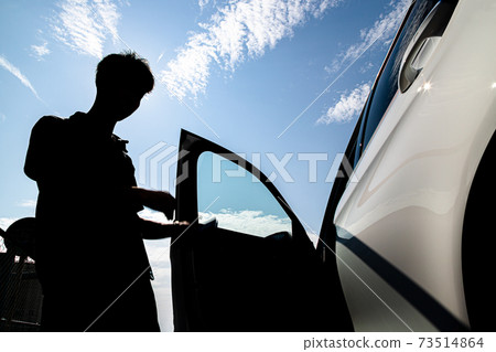 Young man trying to get into the car left steering wheel 73514864