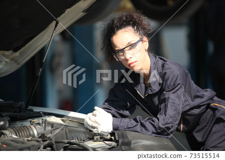 Portrait of a mechanic at work in his garage or car repair service or auto store, business, maintenance and people concept Portrait of a mechanic at work in his garage or car repair service or auto store, business, maintenance and people concept 73515514