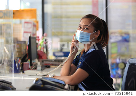 Young woman with face mask back at work in office after lockdown 73515941