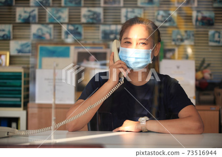 Young woman with face mask back at work in office after lockdown 73516944