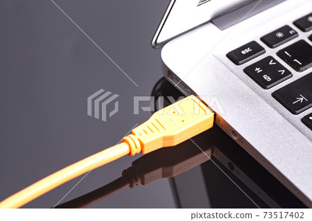 laptop with orange cable on black background 73517402