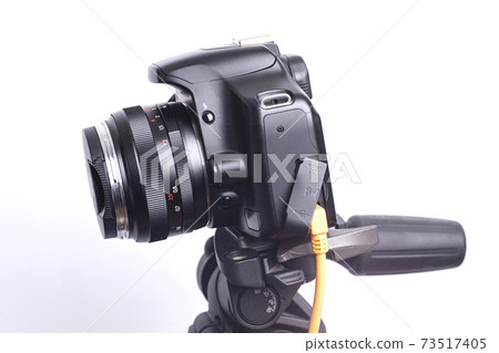 Digital photo camera on black tripod with orange cable Digital photo camera on black tripod with orange cable 73517405