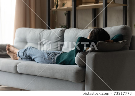 Calm young woman lying on couch at home sleeping 73517773