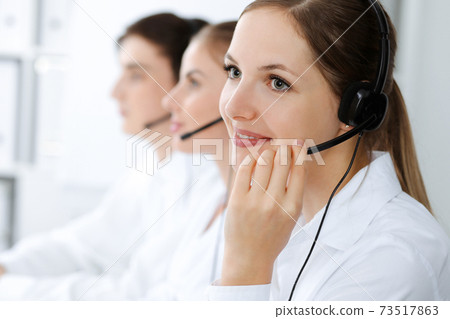 Call center. Beautiful young woman using headset and computer to help customers. Business concept Call center. Beautiful young woman using headset and computer to help customers. Business concept 73517863