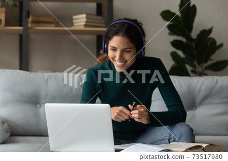 Smiling woman in earphones study on computer at home Smiling woman in earphones study on computer at home 73517980