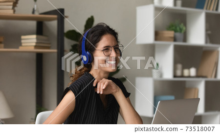 Overjoyed young woman in headphones work on laptop 73518007