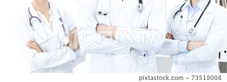 Unknown woman-doctor standing straight with arms crossed in clinic, close-up. Medical team ready to stop coronavirus pandemic. Medicine concept 73518008